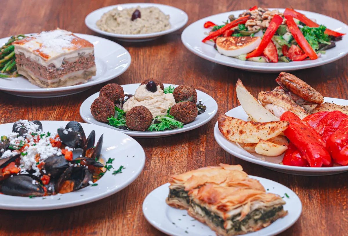 Table spread of dishes: Spinach Pie, Mussels, Falafel, Moussaka and other Greek Dishes